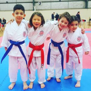 Kids martial arts students smiling in white karate uniforms at a Melbourne dojo